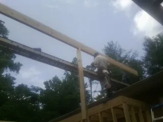 Carpenter setting a ridge beam over a new addition frame — Ice Dam Removal by Roofing Brothers in Rockingham