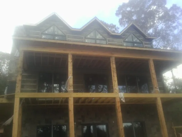 Dormers and porch framing on a large log home under construction — Roof Coating work by our crew in Rockingham