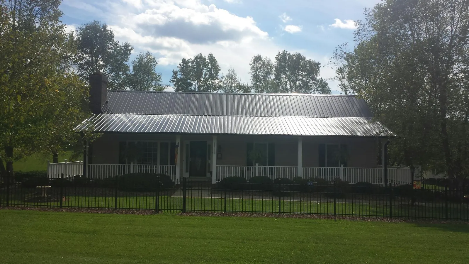 Gray metal roof on a brick ranch with a full width front porch — Gutter Guard Installation work by our crew in Rockingham