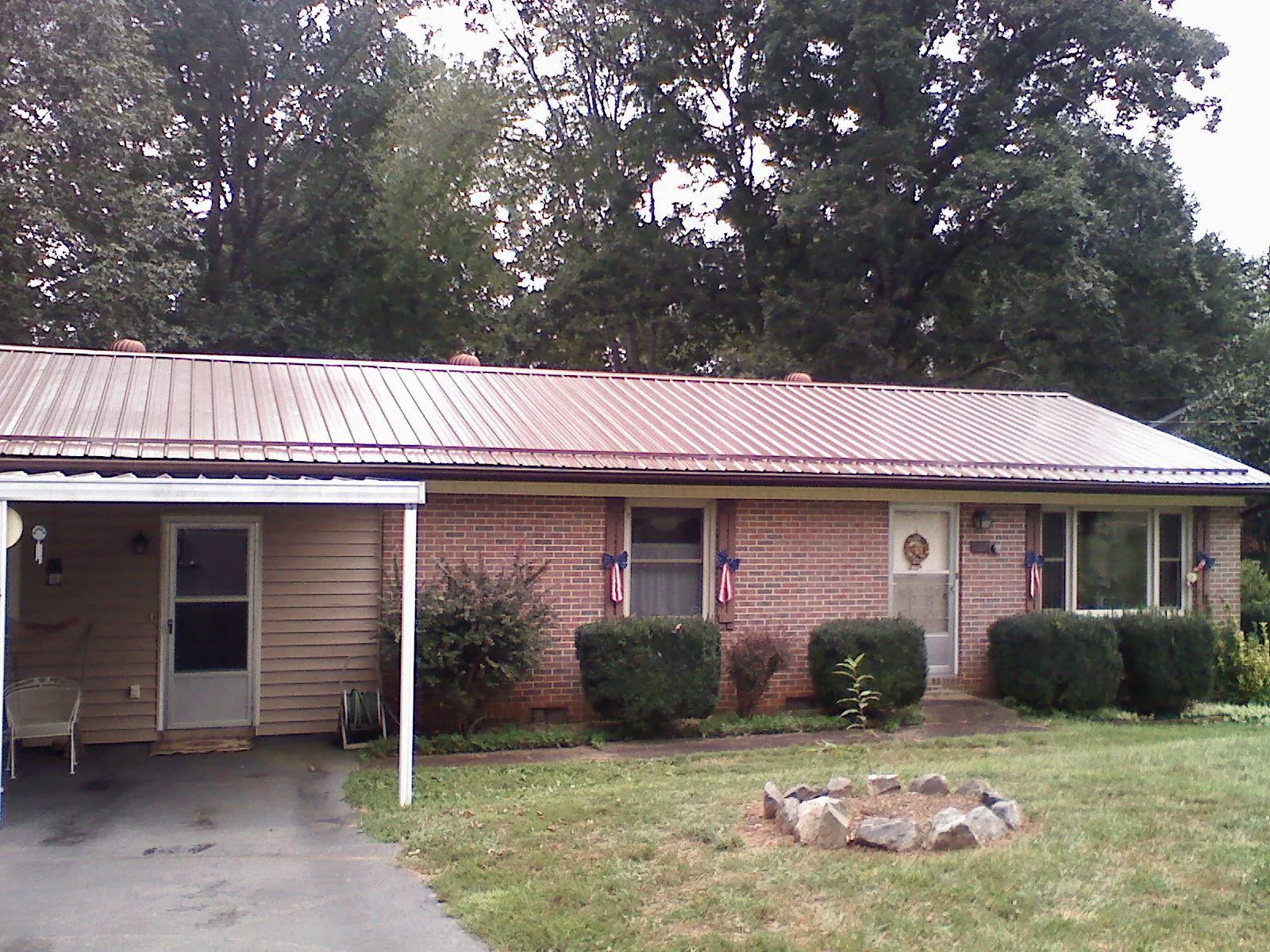 Bronze metal roof and carport on a brick ranch home — Roof Repair work by our crew in Rockingham